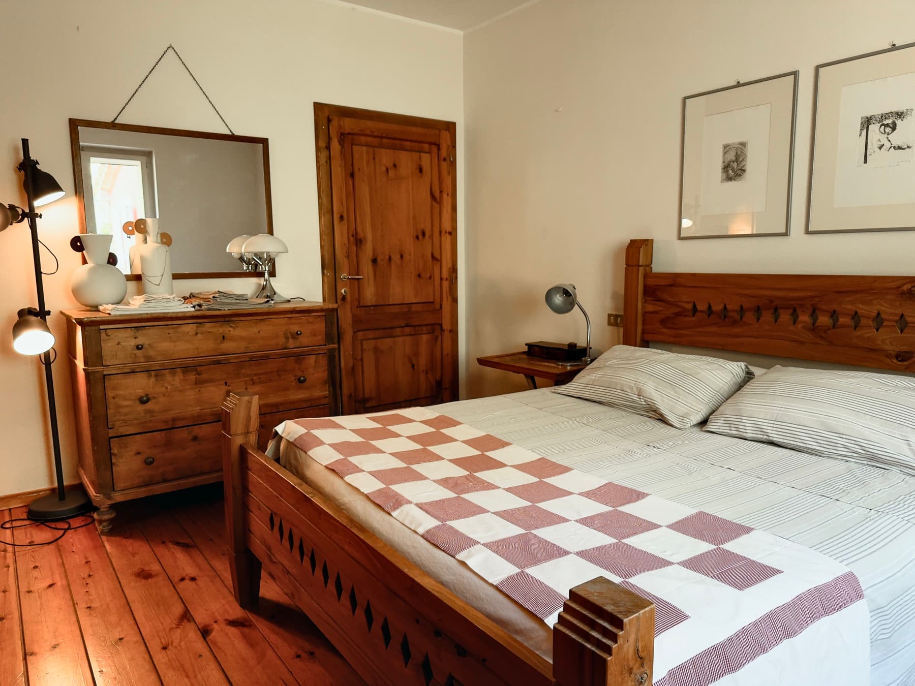 Una camera con il letto a scacchi e la cassettiera in legno